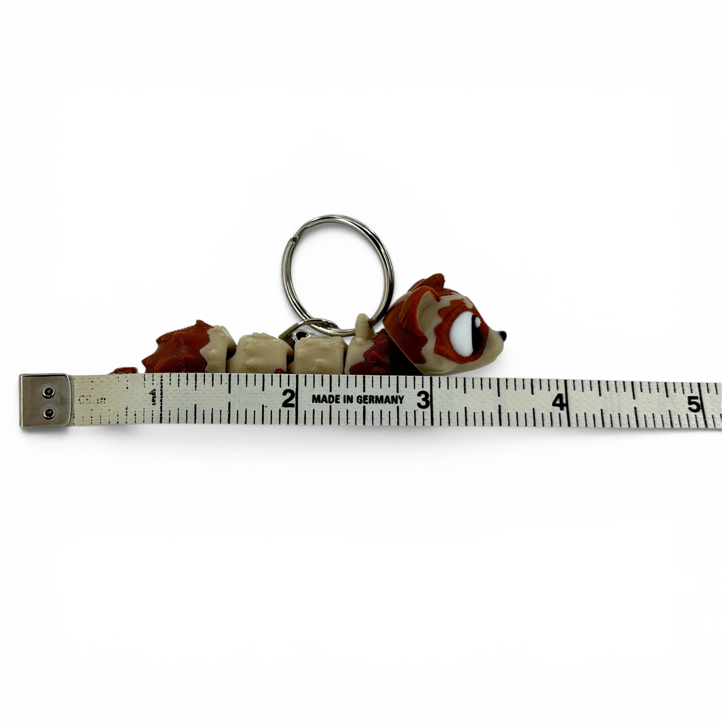 ferret with large eyes keychain on a white background with ruler for scale