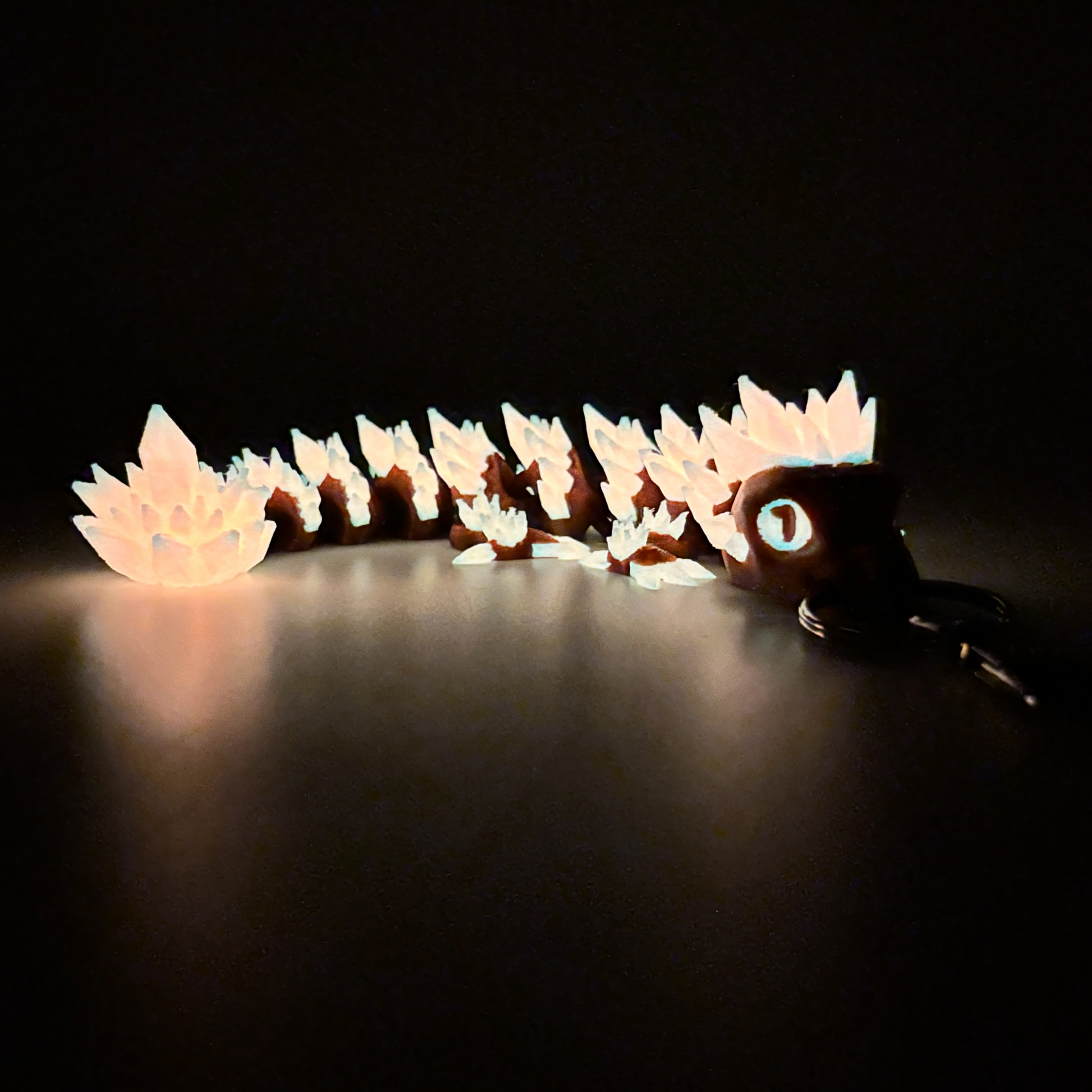 red crystal dragon keychain glowing in the dark on dark background