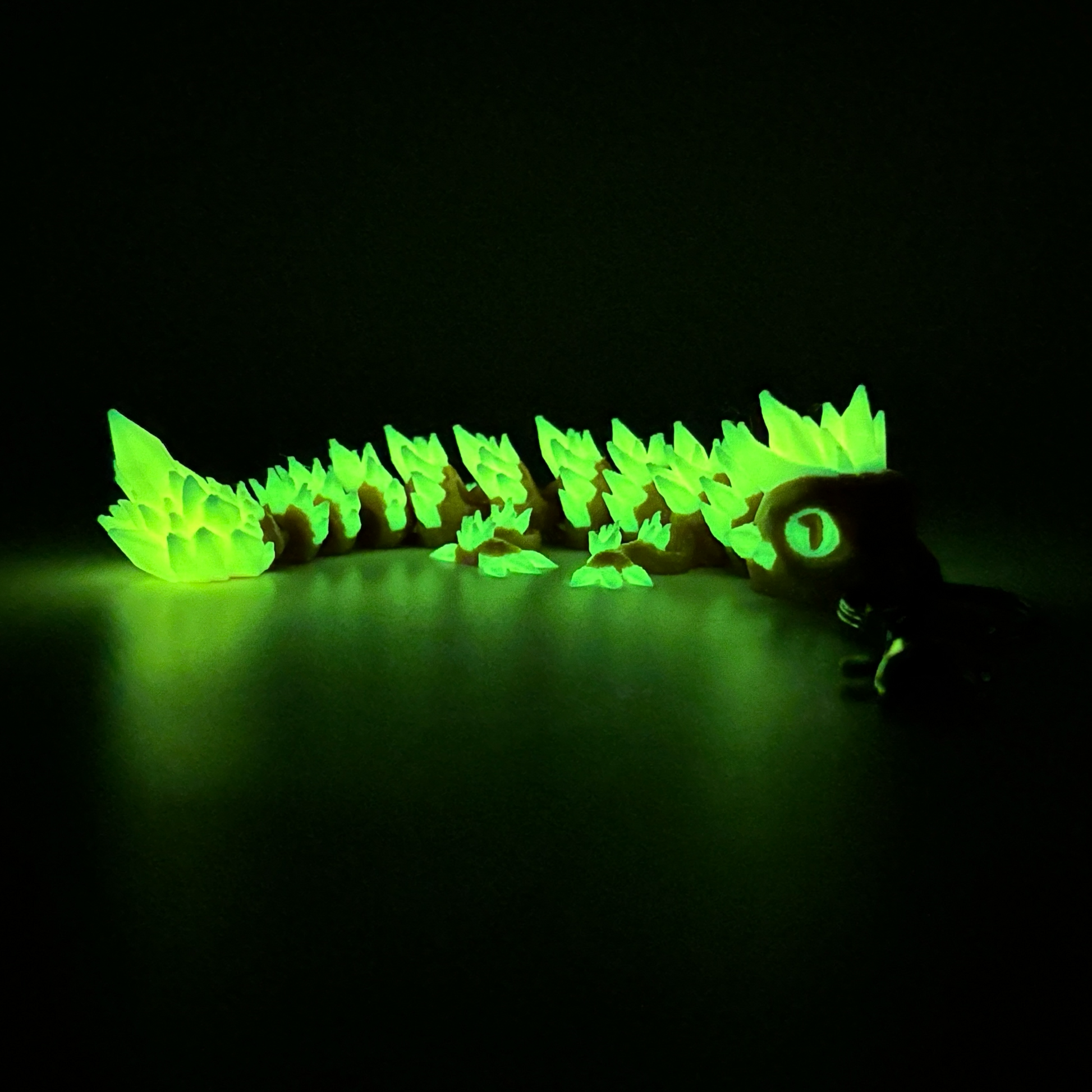 yellow crystal dragon keychain glowing in the dark on dark background