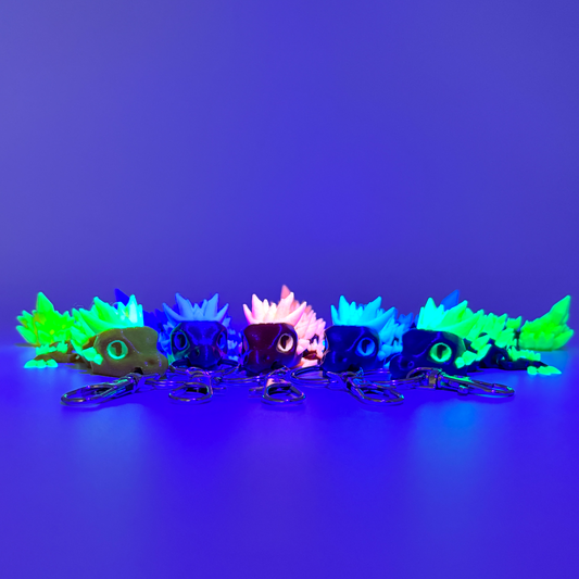 Glowing crystal dragon keychains on a ultraviolet blue background