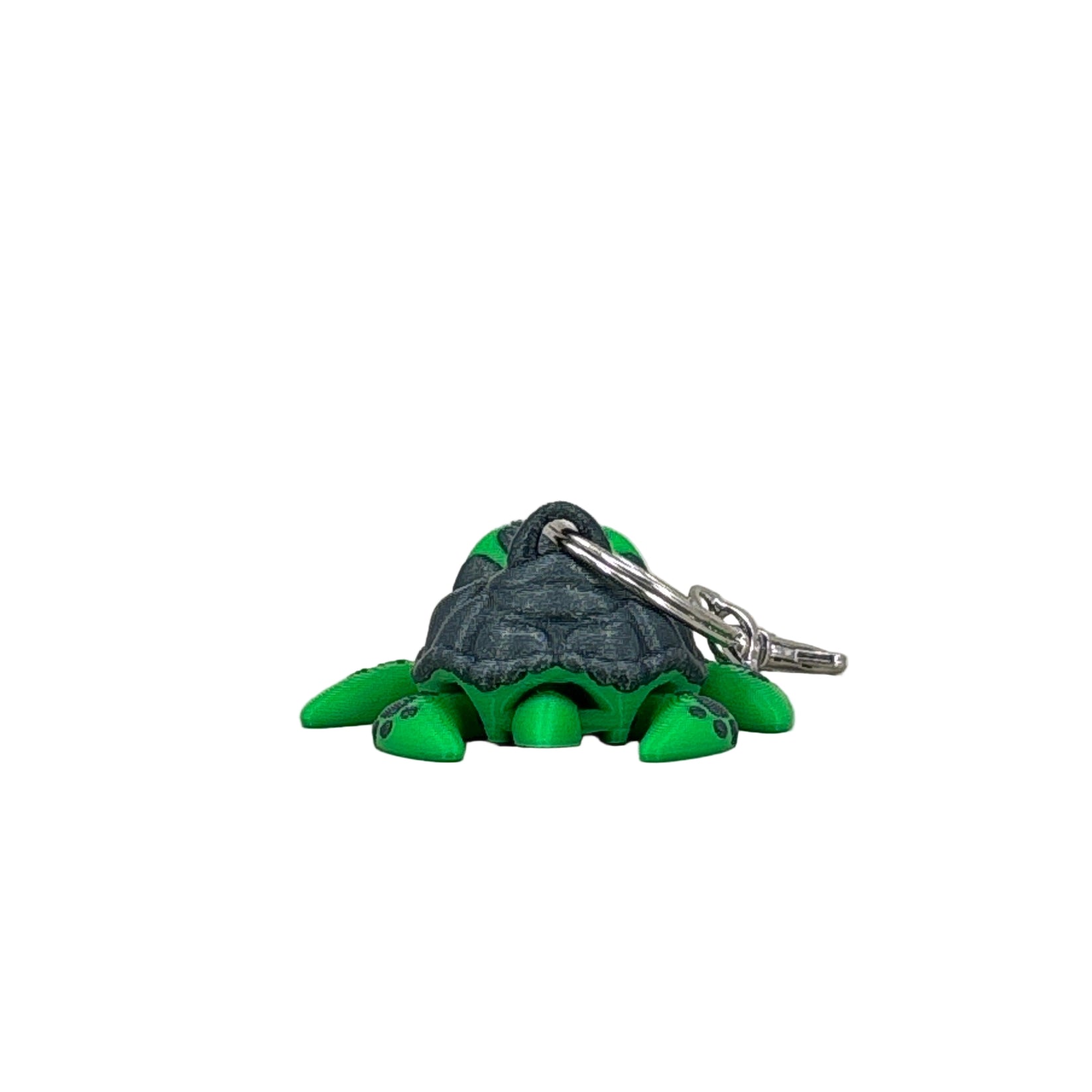 Green and gray turtle-shaped keychain on a light gray background