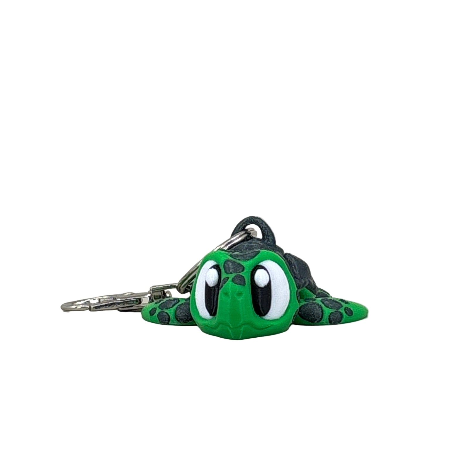 Green and black keychain shaped like a turtle on a light gray background