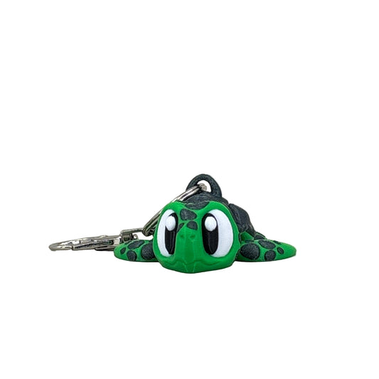 Green and black keychain shaped like a turtle on a light gray background